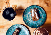 Photo of teal ceramic plates containing baked goods between two cups of coffee.