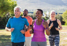 Staying Fit at Any Age Healthy group of mature people jogging on track at park. Happy senior couple running at park with african friends. Multiethnic middle aged friends exercising together outdoor.