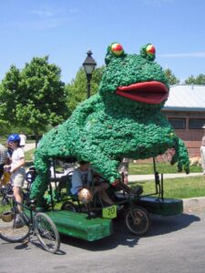 A participant rides a frog-shaped sculpture in a previous Kinetic Sculpture Race