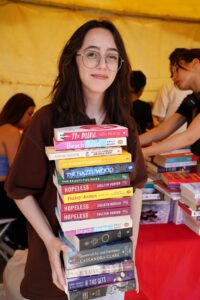 A woman holding a large stack of books
