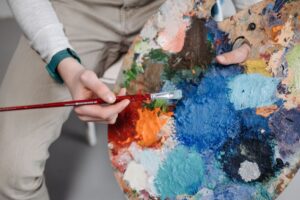 Person painting with a palette covered in paint